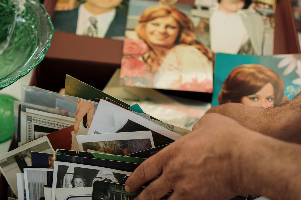 Close-up of hands sorting through a collection of vintage family photos.