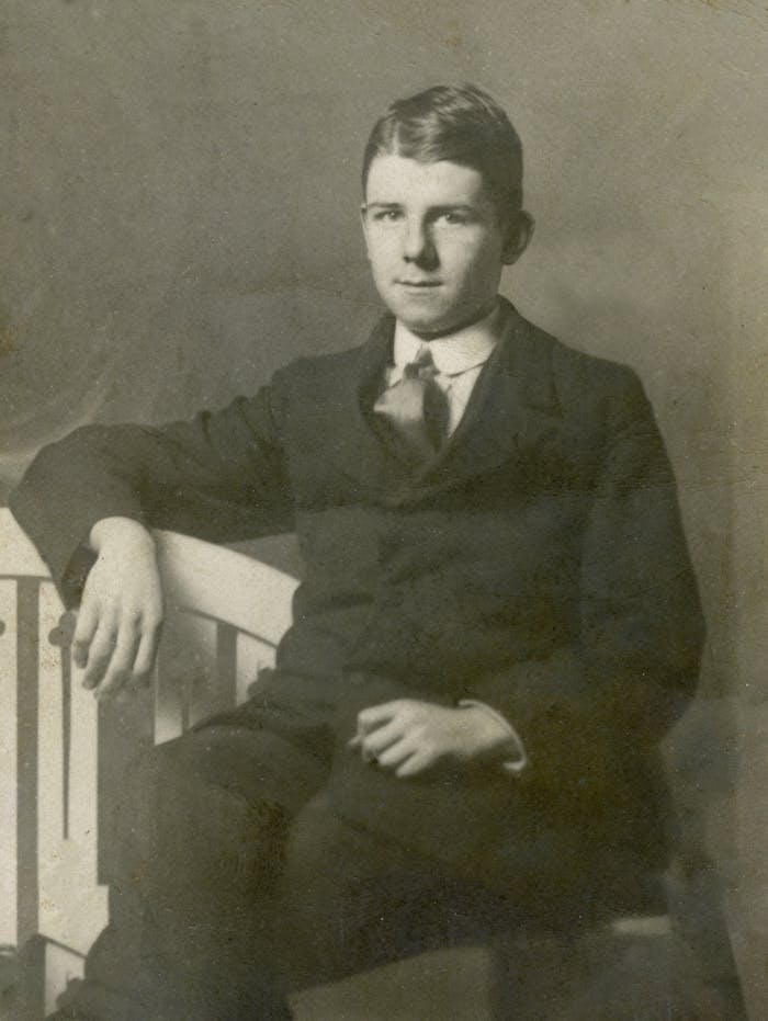 Classic antique portrait of a young man in a formal suit, sitting elegantly.